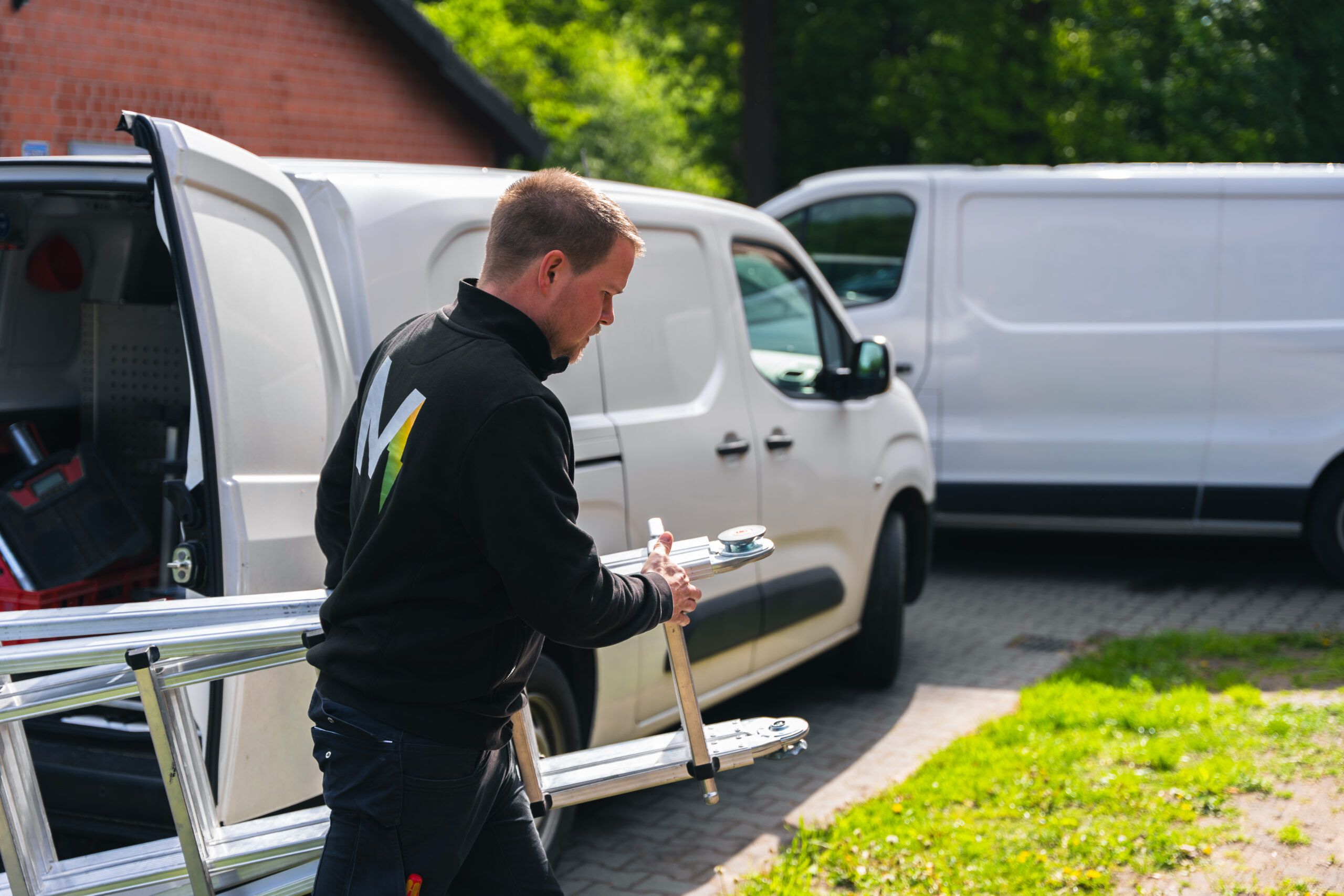 Elektriker von Elektro Mersmann lädt Leiter am Firmenwagen – unterwegs im Einsatz in Harsewinkel und Umgebung
