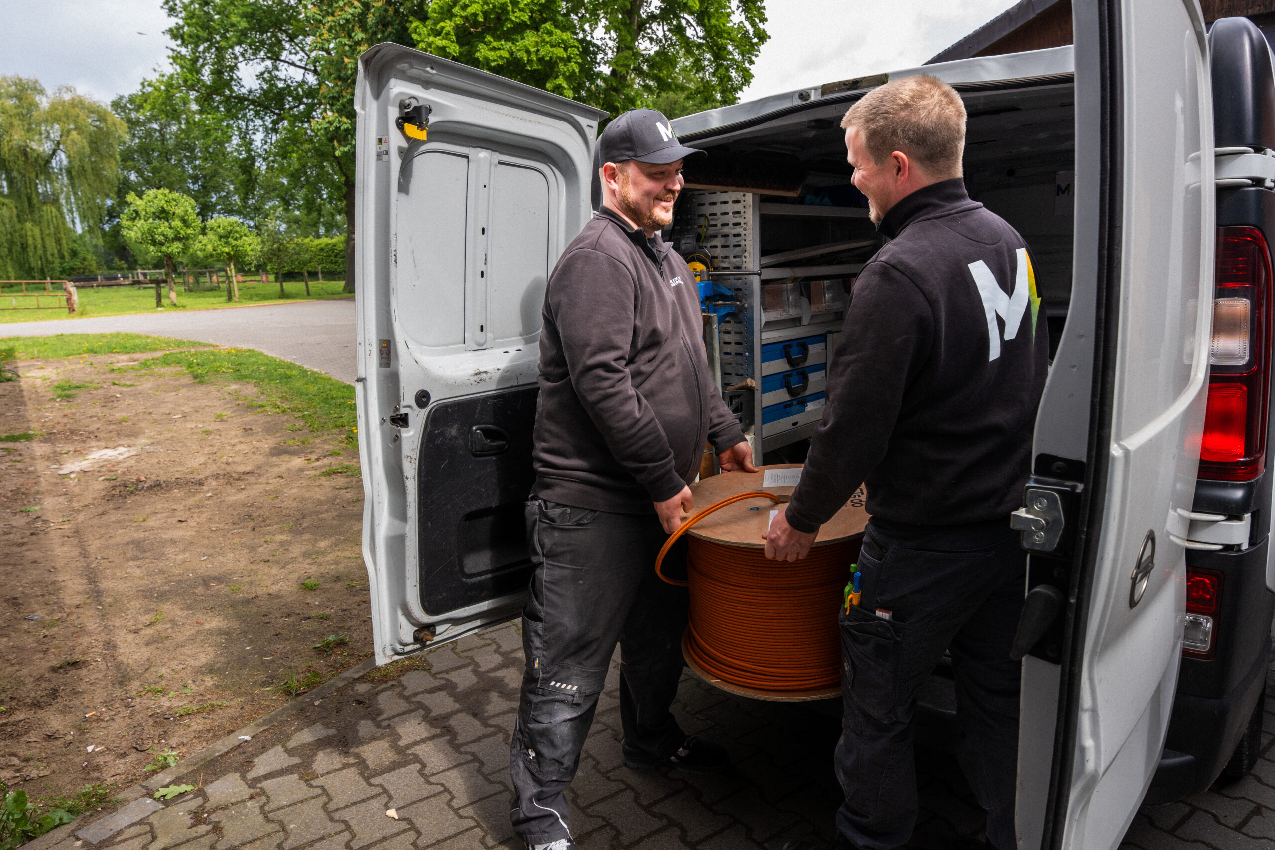 Zwei Elektriker von Elektro Mersmann entladen eine Kabeltrommel aus dem Firmenwagen – unterwegs im Einsatz in Harsewinkel und Umgebung